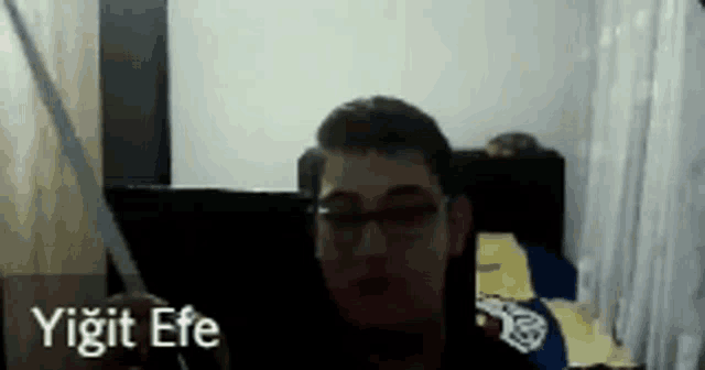a man wearing glasses is holding a piece of paper with the name yiğit efe written on the bottom