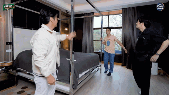 three men are standing in a room with a sign that says fly