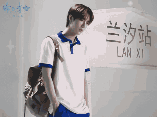 a man with a backpack standing in front of a sign that says lan xi