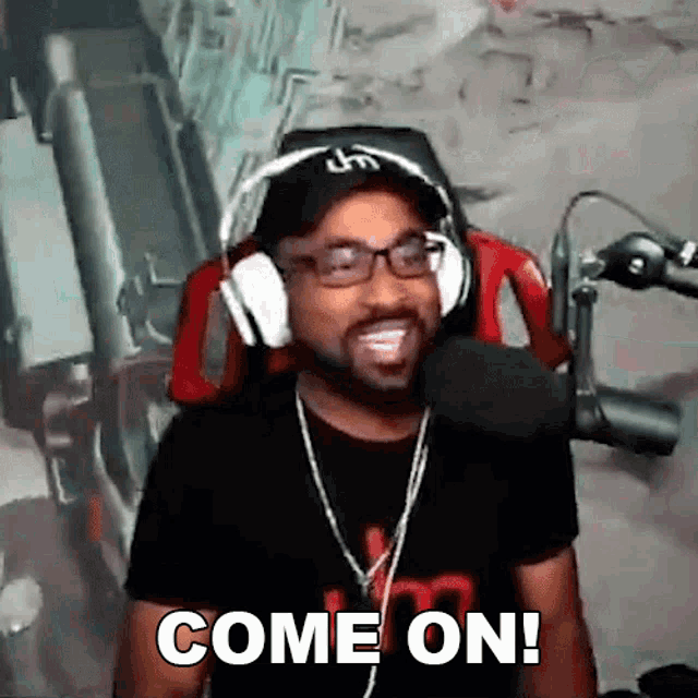 a man wearing headphones and glasses is saying come on in front of a microphone