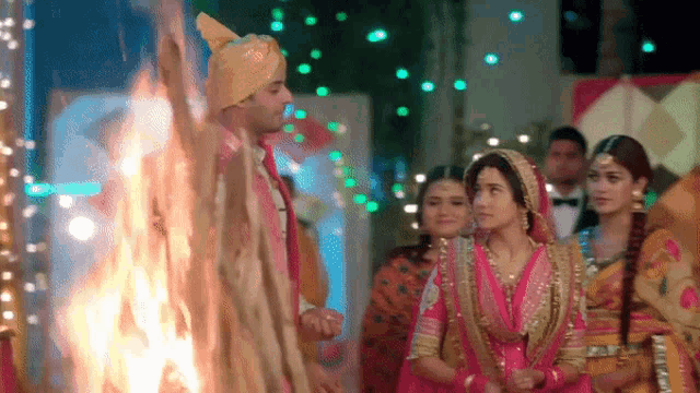 a bride and groom are standing in front of a fire at their wedding
