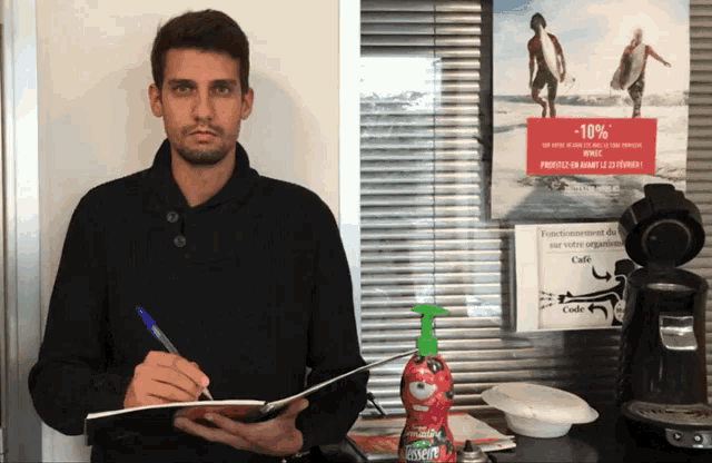 a man is writing on a piece of paper in front of a sign that says cafe