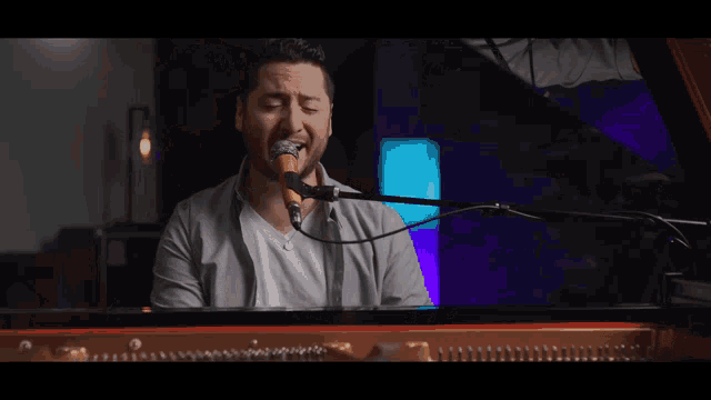 a man is playing a piano and singing into a microphone