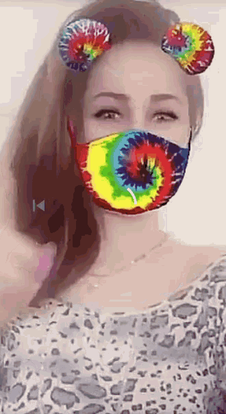 a woman wearing a colorful tie dye face mask with ears