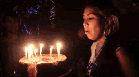 a woman blows out candles on a cake