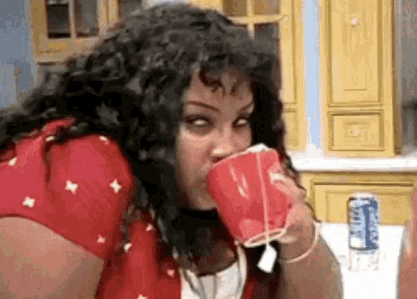 a woman is drinking out of a red cup while sitting at a table .