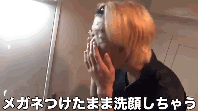 a man is washing his face in front of a mirror in a bathroom in a foreign language .