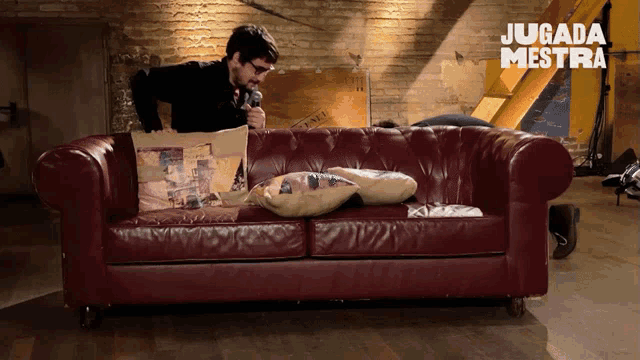 a man sitting on a red leather couch with the words jugada mestra written on the bottom
