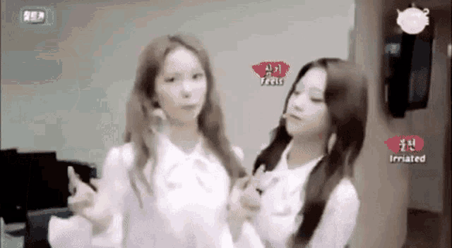 two women are standing next to each other in a room and making funny faces .