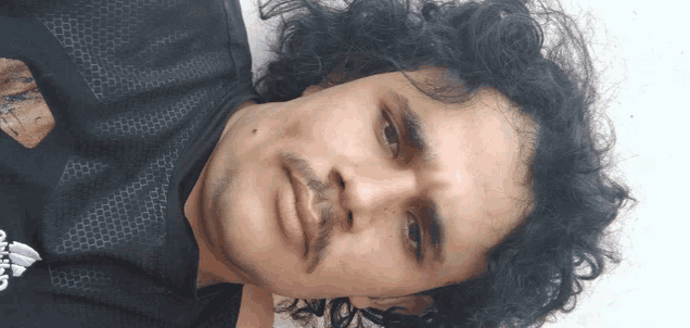a man with curly hair is wearing a black shirt that says adidas on it