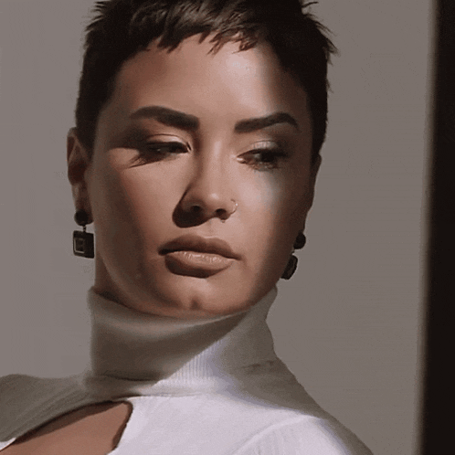 a close up of a woman 's face wearing a turtleneck and earrings