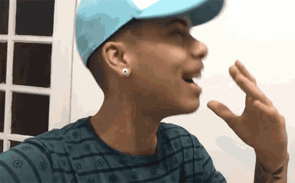 a man wearing a blue hat and earring is talking