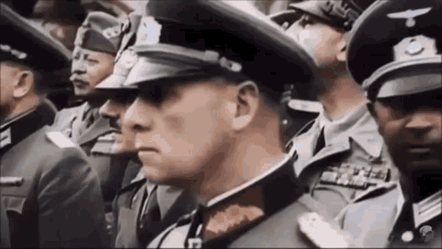 a group of men in military uniforms are standing in a line and looking at something .