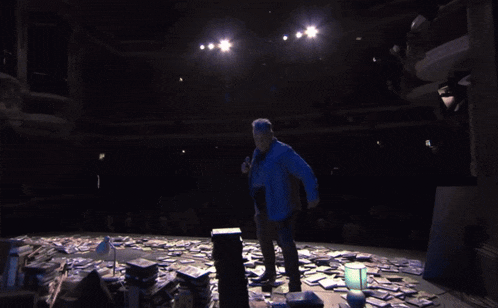 a man stands on a stage with a bunch of cds on the floor