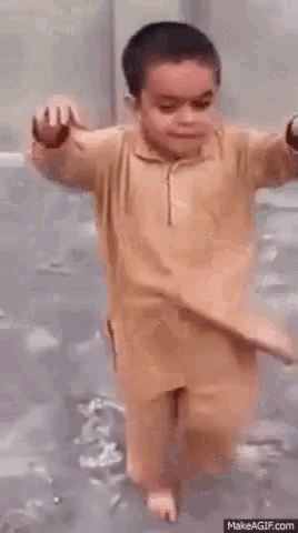 a young boy is making a funny face while standing in a bathtub .
