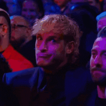 a man is sitting in a crowd of people with purple lights behind him .