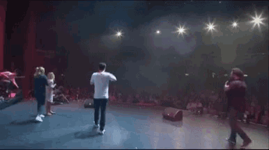 a group of people are dancing on a stage in front of a crowd of people .