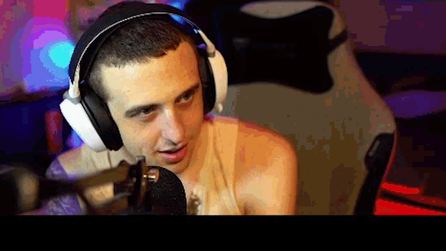 a man wearing headphones and a tank top is talking into a microphone