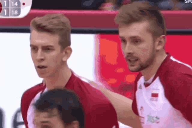 two volleyball players are standing next to each other on a court .