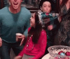 a group of people are standing around a table with a bowl of christmas decorations .