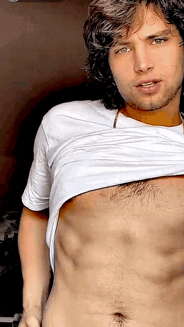 a shirtless man with a beard and green eyes is looking at the camera