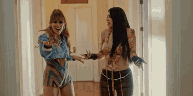 two women are standing next to each other in a hallway and one of them is wearing gloves