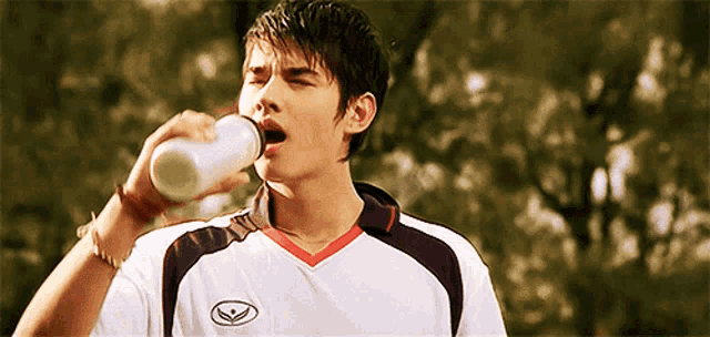 a young man drinking from a bottle with the letter a on the front