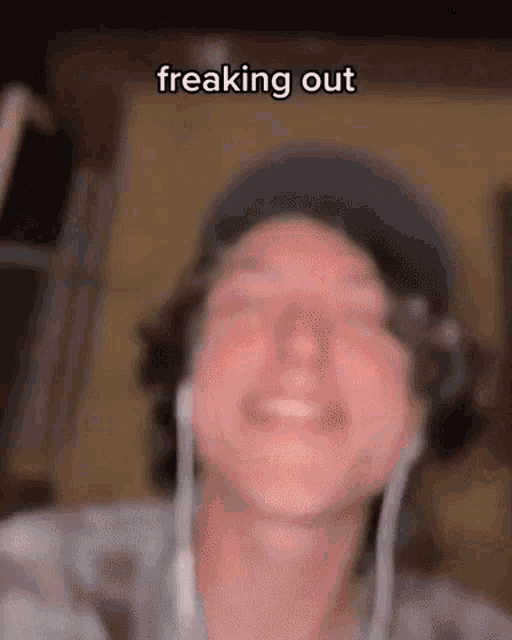 a man wearing headphones and a hat is smiling with the caption freaking out .