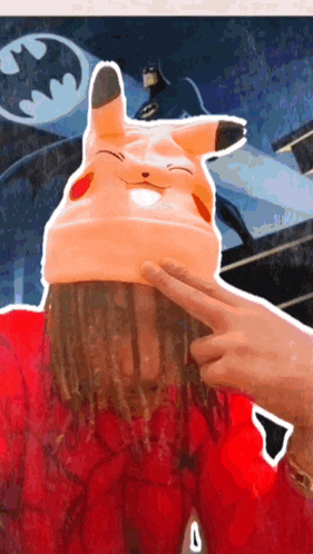 a person wearing a pikachu hat with a batman behind them