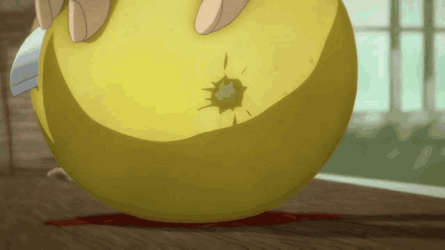 a person is cutting a yellow ball with a knife on a wooden table