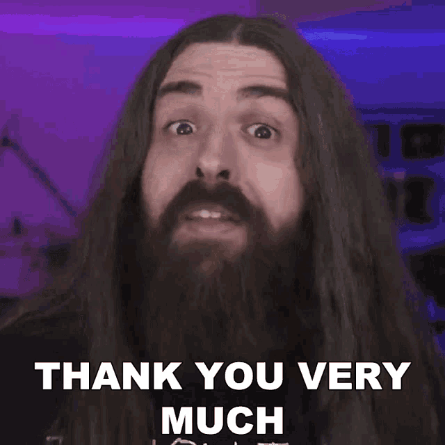 a man with long hair and a beard is giving a thank you very much sign .