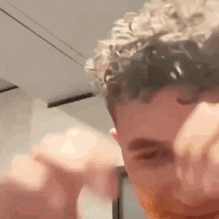 a close up of a man 's face with a beard and curly hair .