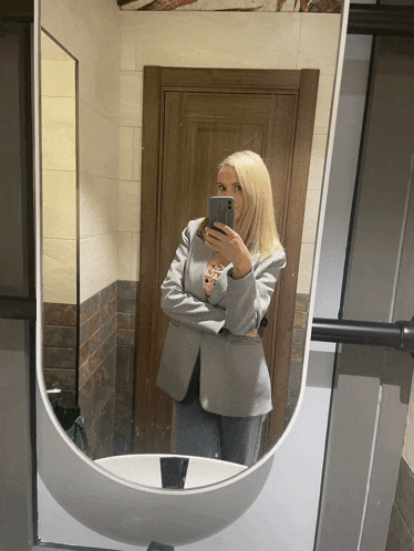 a woman takes a selfie in a bathroom mirror