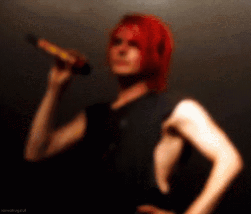 a person with red hair is holding a microphone in their hand .
