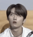 a close up of a young man making a funny face while sitting on a bed .