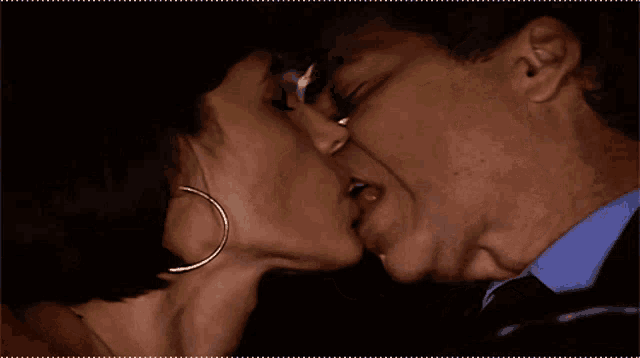 a man and a woman are kissing and the woman has hoop earrings