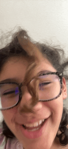 a girl wearing glasses is smiling and making a face