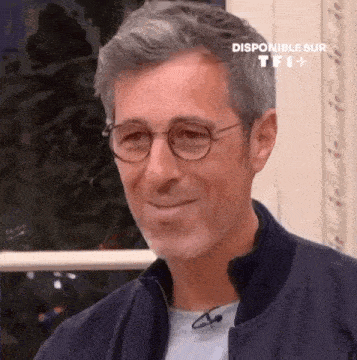 a man wearing glasses and a jacket is smiling at the camera .