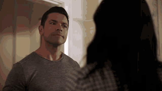 a man and woman are looking at each other and the man is wearing a grey shirt