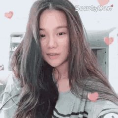 a woman with long hair is taking a selfie with hearts behind her .