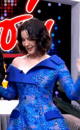 a woman in a blue dress is standing in front of a sign that says t.d.