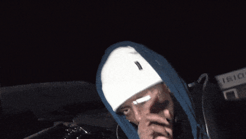 a man wearing a white beanie and a blue hoodie with the letter g on it