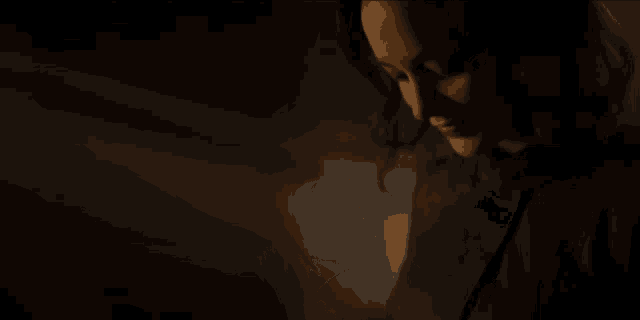 a woman in a dark room is looking down