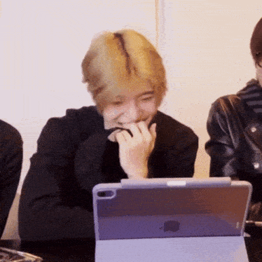 a man is laughing while looking at an apple tablet