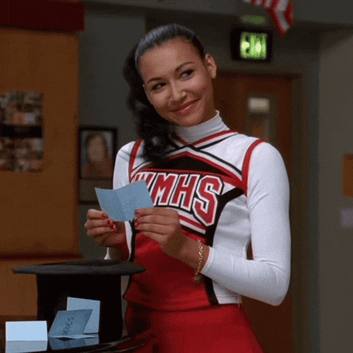 a cheerleader in a mmhs uniform holds a piece of paper in her hands