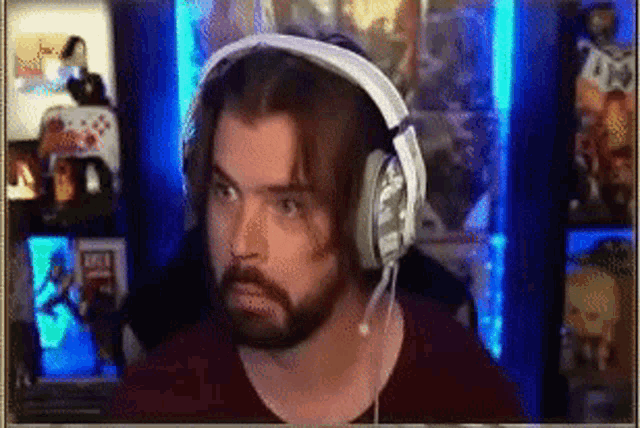 a man with a beard is wearing headphones in front of a blue wall .