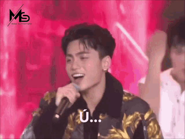 a young man is singing into a microphone with a ms logo on the bottom