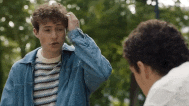 two young men are standing next to each other in a park .