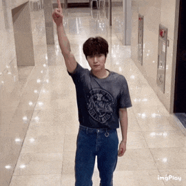 a young man is standing in a hallway with his arm up .