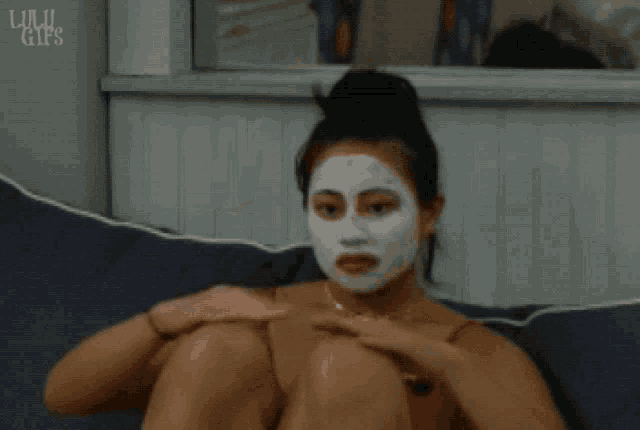 a woman with a white mask on her face is sitting on a couch with her arms crossed ..